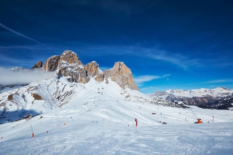 View of a ski resort piste with people skiing in Dolomites in Italy