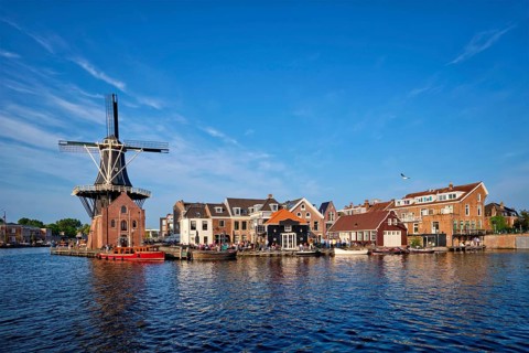 Harlem cityscape, landmark windmill De Adriaan on Spaarne river with boats. Harlem, Netherlands