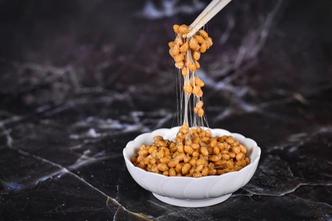 Traditional Japanese food Natto made from fermented soybeans drawing sticky strings on chopsticks