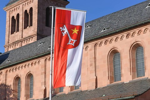 Red and white flag with city arms of city Worms in Germany showing a white key and a five pointed