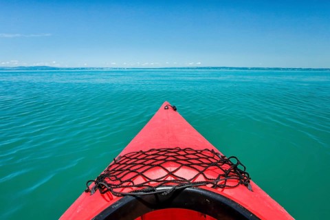 Bow of red kayak with view over the expanse and turquoise waters of Lake Constance