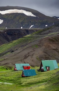 Cabins among volcanic landscape with black sand and green grass, Ásgarður, Kerlingarfjöll,