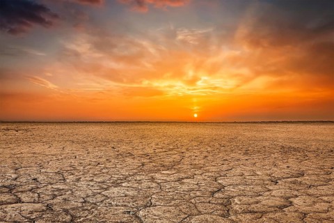 Global worming concept, cracked scorched earth soil drought desert landscape dramatic sunset