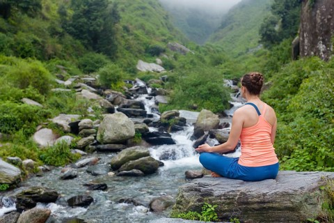 Woman doing yoga outdoors at waterfall