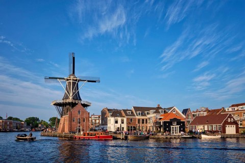 Harlem cityscape, landmark windmill De Adriaan on Spaarne river with boats. Harlem, Netherlands