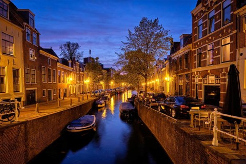 Typical Netherlands view, canal with boats and houses illuminated in the evening. Haarlem,