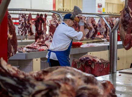 Man chopping meat and bones, butcher's shop with fresh meat, market at Osh bazaar, Bishkek,