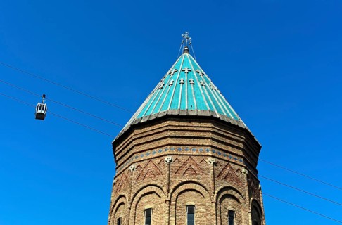 Two cabins of the Rike-Narikala cable car pass the tower of St George's Armenian Church, Tbilisi,