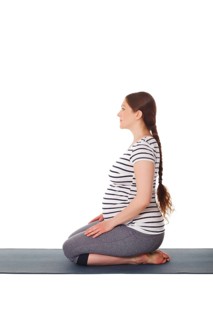 Pregnancy yoga exercise, pregnant woman doing yoga asana Virasana Hero Pose on knees isolated on