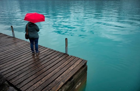 Older woman, best-ager, with red umbrella, bad weather, lakeside promenade at Lake Brienz, Brienz,