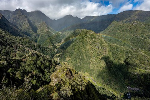 Densely overgrown steep mountains with rainbow, green mountain landscape, view from Miradouro dos