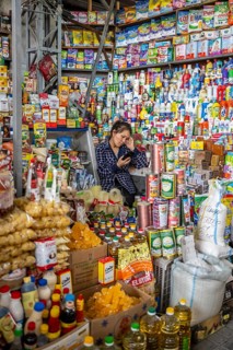 Woman surrounded by many products in her stall, consumption, market stall at Osh bazaar, Bishkek,