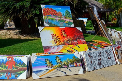 A collection of colourful paintings presented on a sunny day outdoors, with various landscape and