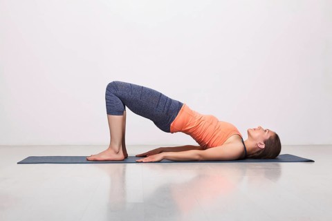 Beautiful sporty fit yogini woman practices yoga asana setu bandhasana, bridge pose beginner