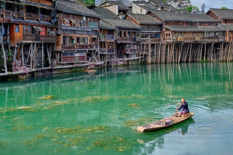 FENGHUANG, CHINA, APRIL 23, 2018: Unidentified chinese man in boat Feng Huang Ancient Town (Phoenix