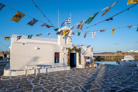 White Cycladic Greek Orthodox Church of Agios Nikolaos, decorated with flags, harbour of Naoussa,