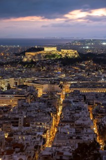 View over the sea of houses of Athens, illuminated Parthenon temple on the Acropolis, dramatic