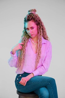 Young woman touching her dreadlocks and looking forward
