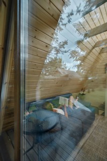 View through the window at young woman on sofa inside summer house reading a book