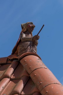 Figure of a witch on the roof ridge of a residential house, blue sky, Zeil am Main, Lower