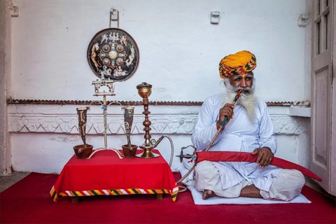 JODHPUR, INDIA, NOVEMBER 26, 2012: Old Indian man smokes hookah (waterpipe) in Mehrangarh fort. The