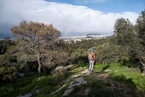 Tourist looking over the city with rainbow, Philopappos Hill, in the evening light, Athens, Attica,
