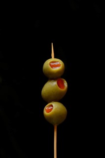 Green olives on fork, stuffed with pieces of paprika