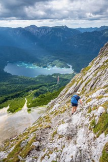 Via ferrata over the Riffelscharte, hiker in the mountains, view of Eibsee lake and Werdenfelser