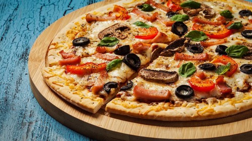 Panorama of ham pizza with (capsicum), mushrooms, olives and basil leaves on wooden board on blue