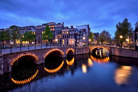 Night view of Amterdam cityscape with canal, bridge and medieval houses in the evening twilight