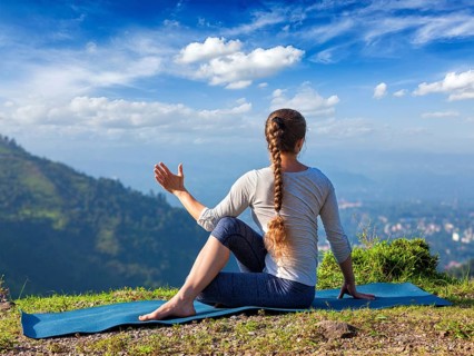 Hatha yoga outdoors, sporty fit woman doing yoga asana Parivrtta Marichyasana (or ardha