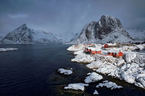 Iconic Hamnoy fishing village on Lofoten Islands, Norway with red rorbu houses. With falling snow