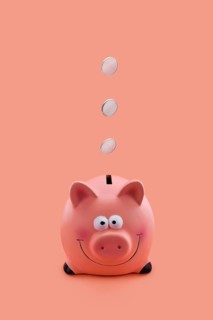 Pink piggy bank with coins falling down