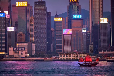 HONG KONG, CHINA, MAY 1, 2018: Tourist junk boat ferry with red sails and Hong Kong skyline