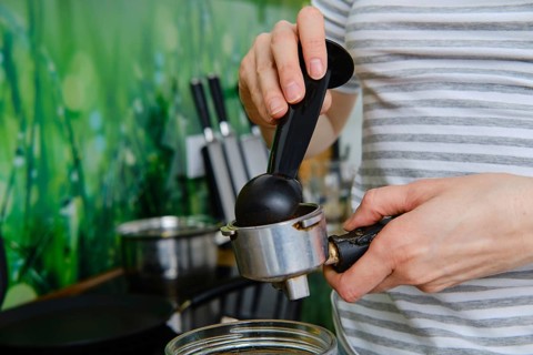 Closeup view of female hands making ground coffee in coffee machine