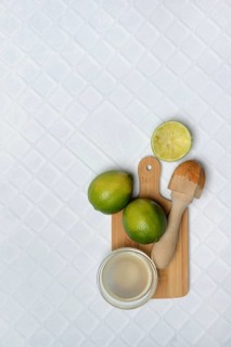 Limes, squeezed, with citrus juicer on chopping board and lime juice in small bowls