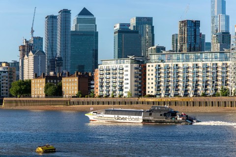 Uber boat water bus service passing Canary Wharf, Isle of Dogs, London, England, UK