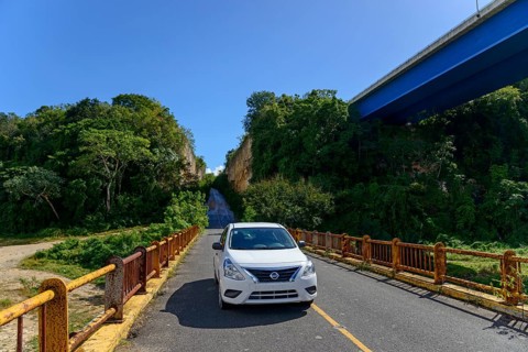 Car parked in the sun on one of the two bridges over the Chavon River surrounded by lush