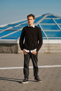 Outdoor portrait of a young man in white shirt sticking out from under a sweater