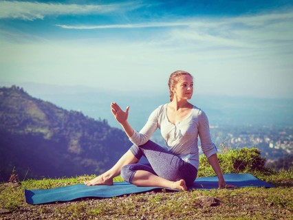 Yoga exercise outdoors, woman doing Ardha matsyendrasana asana, half spinal twist pose mountains in