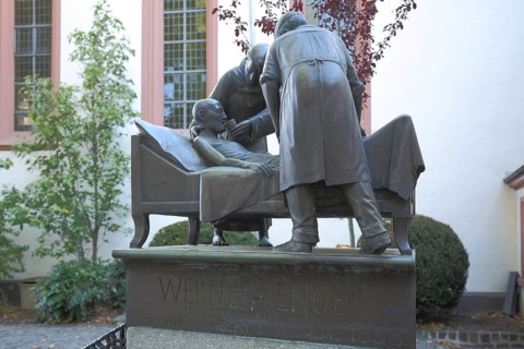 Sculpture and memorial to Werner Senger, three, figures, bed, lie, help, care, sick person,