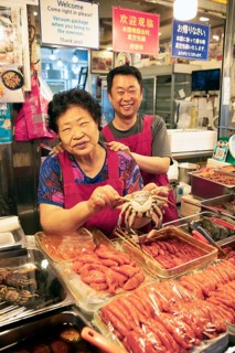 Korean woman and Korean man with a crab, Gwangjang market, traditional street market in Jongno-gu,
