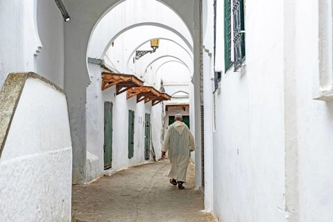 Moroccan Muslim man wearing traditional Islamic djellaba, jillaba walking in medina of the city