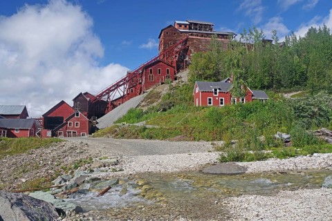 Crystal-clear stream and old industrial ruins on the hillside, copper mining, red wooden buildings,