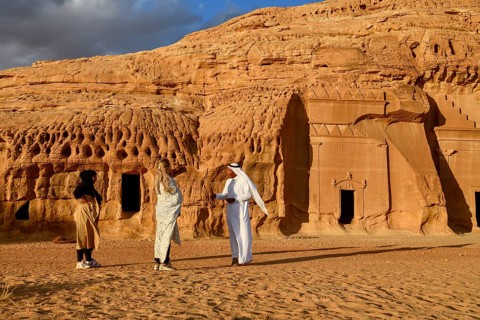 Tourists in front of the Nabataean tombs at the rock Qasr Al-Bint, Hegra or Mada'in Salih, AlUla