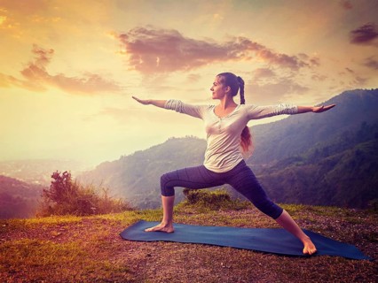 Yoga outdoors, sporty fit woman doing Ashtanga Vinyasa Yoga asana Virabhadrasana 2 Warrior pose