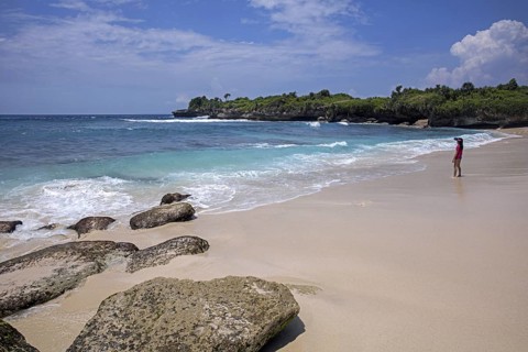 Girl looking at waves on Dream beach, white sand beach on the island Nusa Lembongan near Bali in