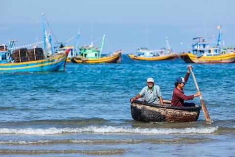 PHAN THIET, VIETNAM, 5 JUNE, 2011: Two fishermen in a coracle boat returning from fishing. Phan