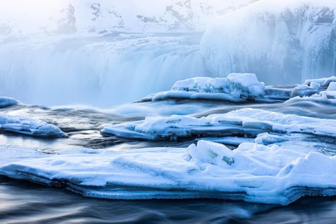 Icefall at the edge of the Godafoss waterfall at dawn, snow-covered landscape, Northern Iceland