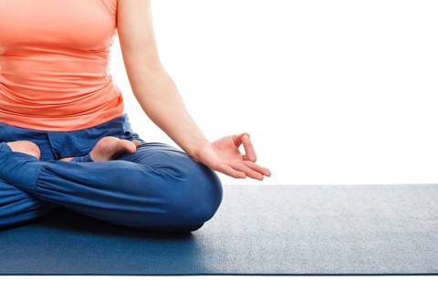 Close up of of woman in yoga asana Padmasana (Lotus pose) cross legged position for meditation with